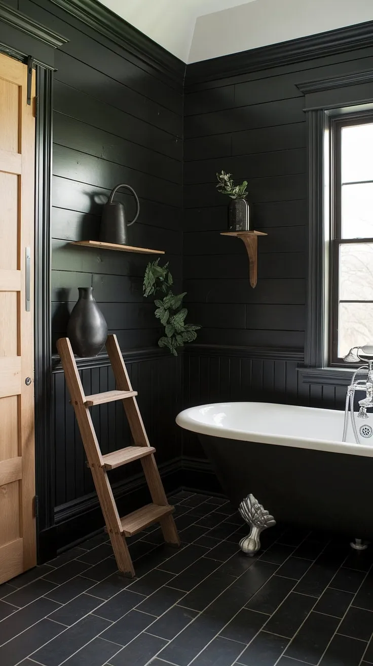 A stunning example of black bathroom decor ideas, this all-black bathroom features black shiplap walls and black wainscoting for a sophisticated and dramatic effect. The black tile bathrooms floor creates a cohesive look, while the clawfoot tub near the window, accented by a wooden ladder, provides a focal point. This black and wood bathroom demonstrates how to seamlessly blend dark tones with natural wood elements. Consider this space for your next black bathroom walls project or when exploring clawfoot tub ideas.