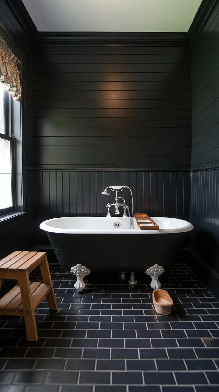 Dark luxury redefined. This black bathroom wainscoting and black bathroom walls, paired with a clawfoot tub on a wooden platform, offer unique black bathroom decor ideas. Explore the elegance of black tile bathrooms and black shiplap in this captivating space.