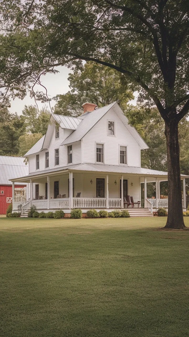 Waking up to a picturesque white farmhouse with a wraparound porch, lush greenery, and a charming red barn is the ultimate countryside dream.