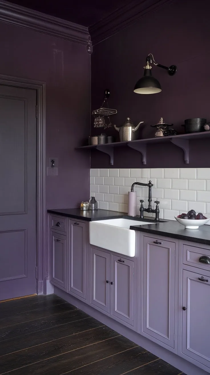Dark purple walls and white cabinetry create a dramatic contrast in this gothic-inspired kitchen, where even the fruit seems to embrace the mysterious ambiance. The black accents and dark wood flooring complete the alluring, feminine space. A perfect blend of light and shadow, this kitchen is a testament to sophisticated design.