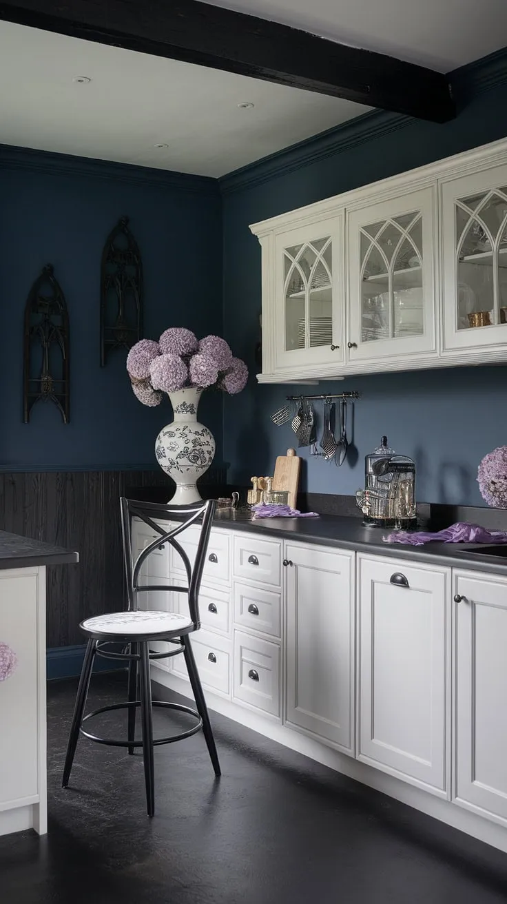 A touch of feminine grace in a gothic setting. This kitchen's dark blue hues and black accents are balanced by the bright white cabinets and a delicate vase of purple flowers. The black chair and dark gray floor add to the sophisticated, moody atmosphere, creating a space that is both dramatic and inviting. A truly unique and captivating design.