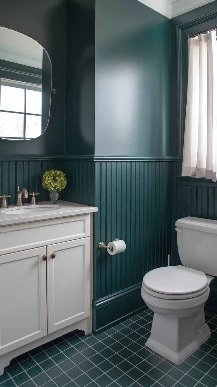 This small guest bathroom proves that a monochromatic green palette can be incredibly chic. The dark green wainscoting, extending from floor to halfway up the wall, creates a sophisticated foundation, complemented by the matching wall paint and green and white tiled floor.  Green bathroom decor doesn't get more stylish than this.  Perfect example of green guest bathroom ideas.