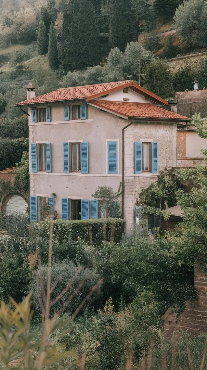 Nestled in Northern Italy, this enchanting villa with its vibrant red roof and blue shutters is a postcard-perfect summer retreat that captures the essence of European charm.