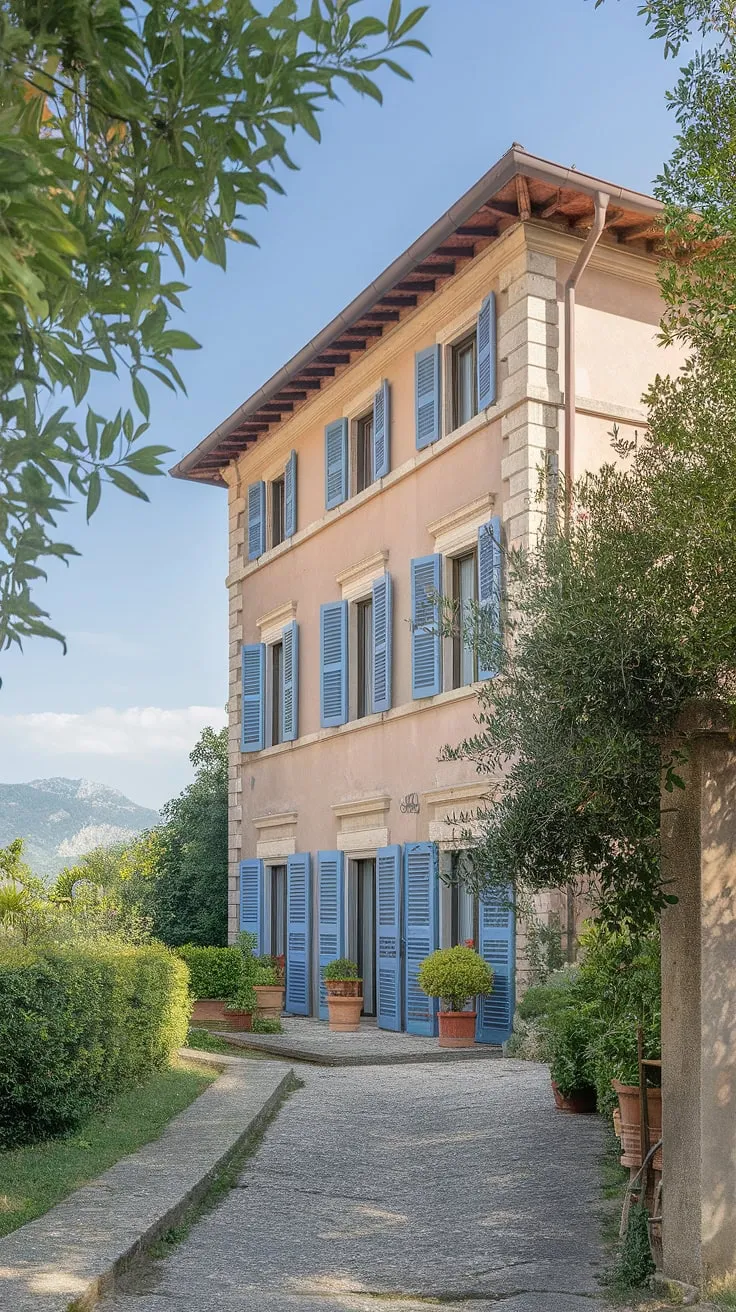 A sun-drenched Italian villa, nestled in Northern Italy's verdant hills, beckons with its terracotta roof, blue shutters, and charming cobblestone path.