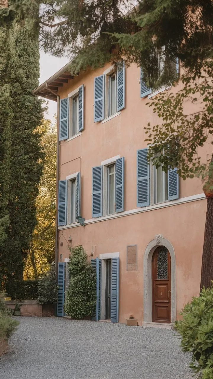 In the heart of Northern Italy, a sun-kissed villa with terracotta walls and vibrant blue shutters invites you to uncover its tranquil secrets along a time-worn gravel path.