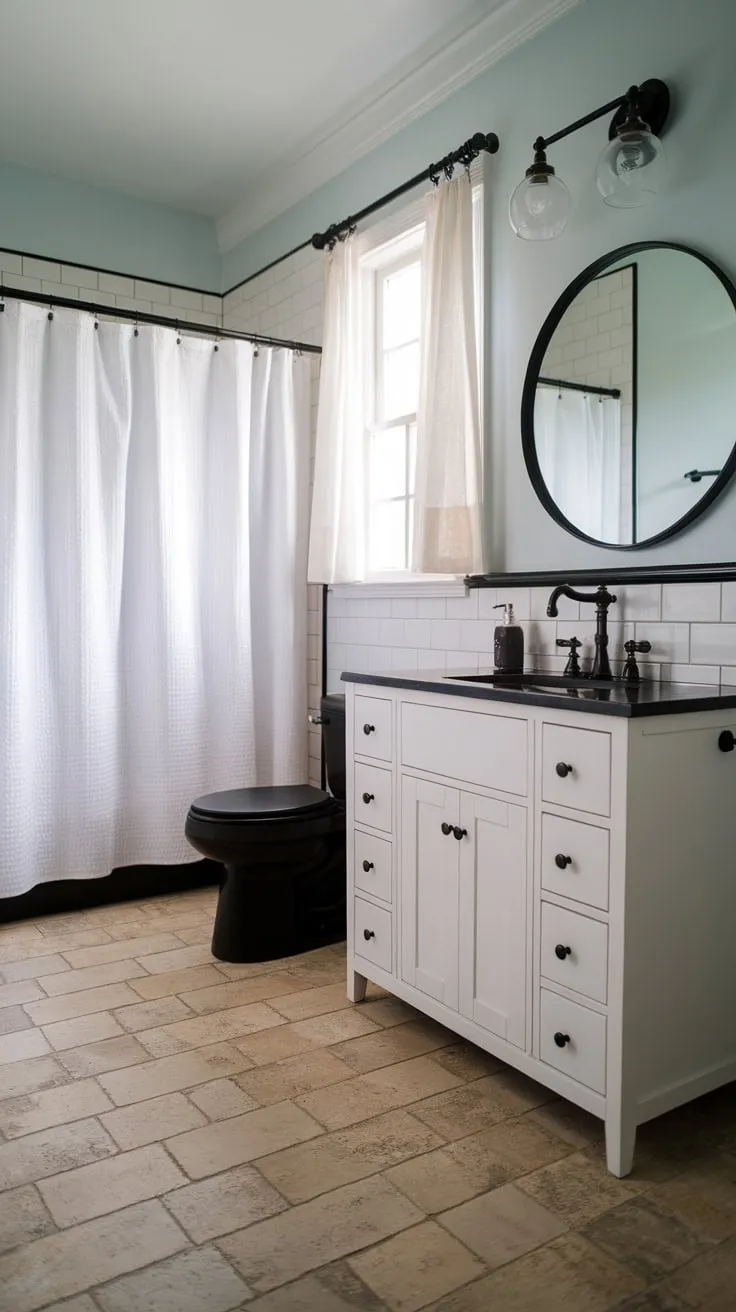 Light blue walls and a chic black-and-white vanity highlight this modern farmhouse bathroom's calming, tiled space.