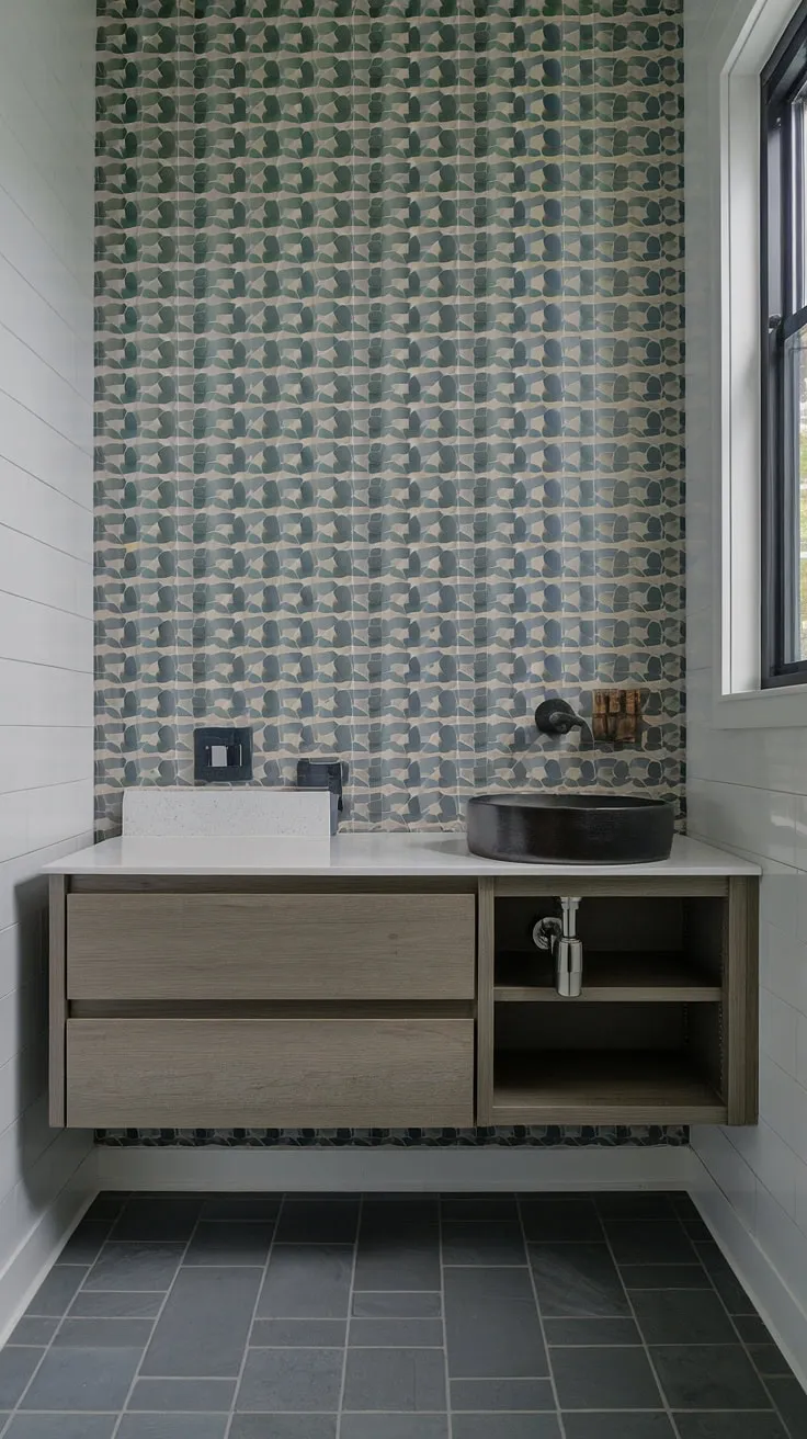 Sleek and sophisticated, this powder room boasts a floating vanity with a striking black sink, showcasing a perfect blend of modern design and functionality. The patterned wallpaper adds a touch of personality, while the grey tile floor complements the overall aesthetic. A small space, maximized.