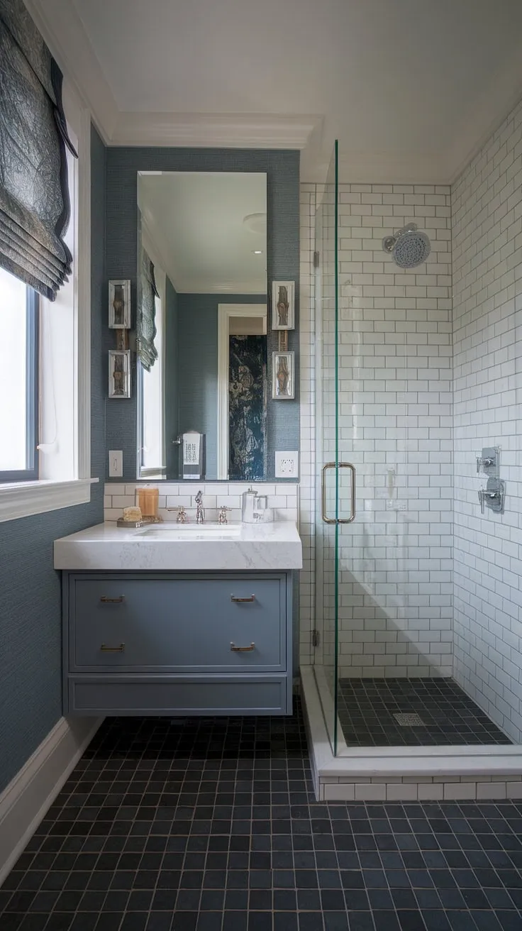 This small but perfectly formed powder room boasts a luxurious feel. The white marble vanity, framed by a stylish mirror and blue patterned wallpaper, is complemented by a modern glass shower and a chic black and white tiled floor. A testament to how impactful even a compact space can be.