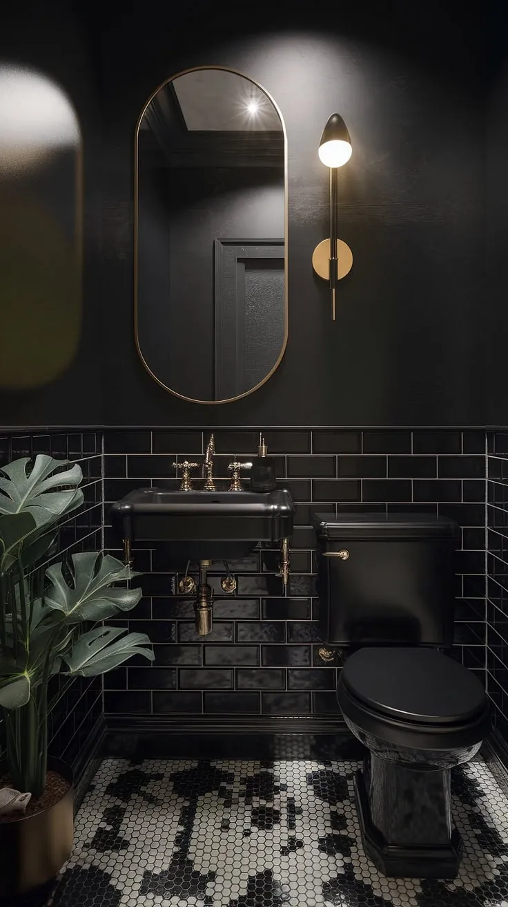 This moody powder room features a luxurious black theme with a striking black sink, toilet, and wall, accented by a gold light fixture and mirror, creating an elegant atmosphere in dark bathrooms.