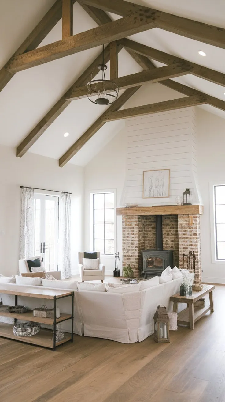 A large sectional dominates a high-ceilinged modern farmhouse living room warmed by a wood-burning stove nestled within a charming brick fireplace.