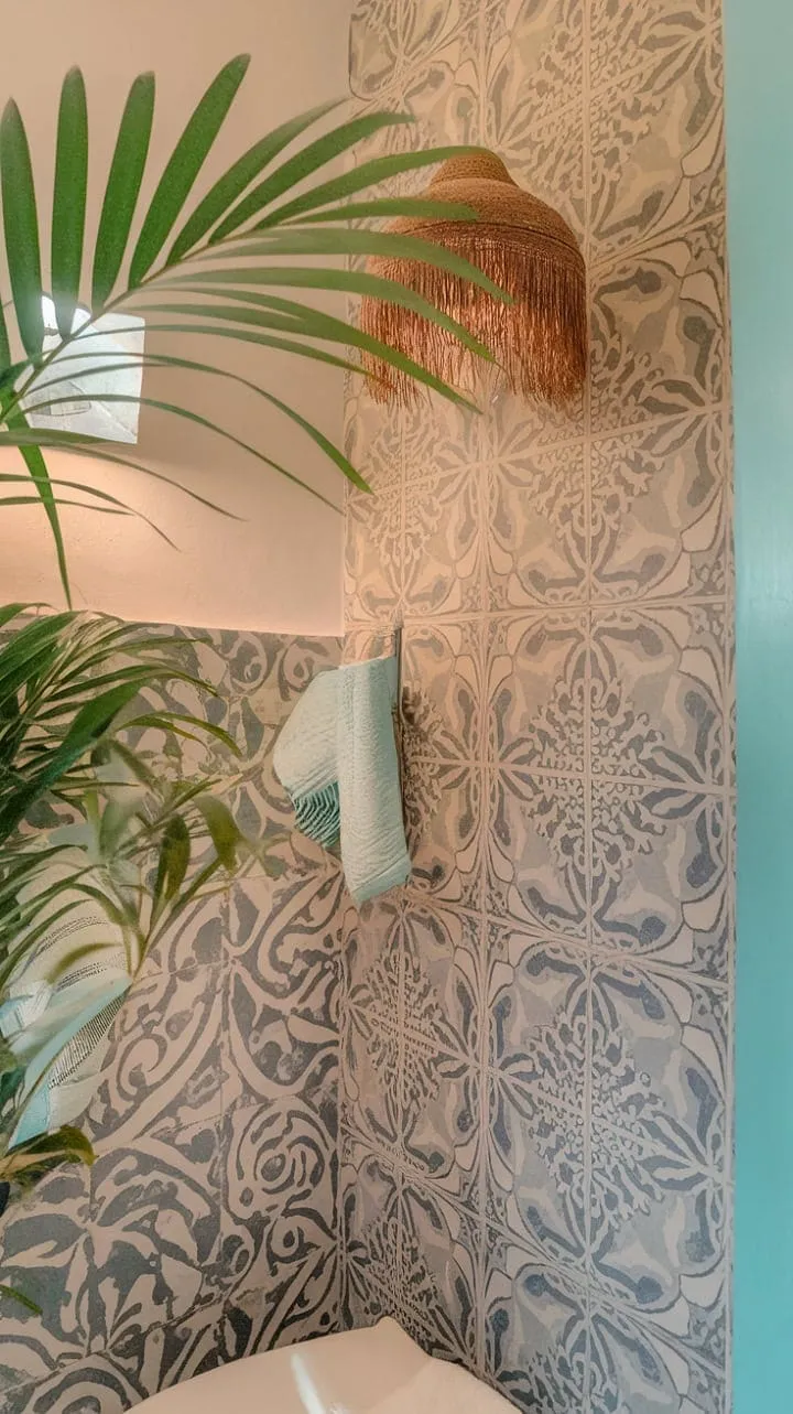 Transform your bathing experience into a sun-soaked retreat with vibrant Mediterranean tiles, boho chic decor, and a lush plant that together create a serene oasis.