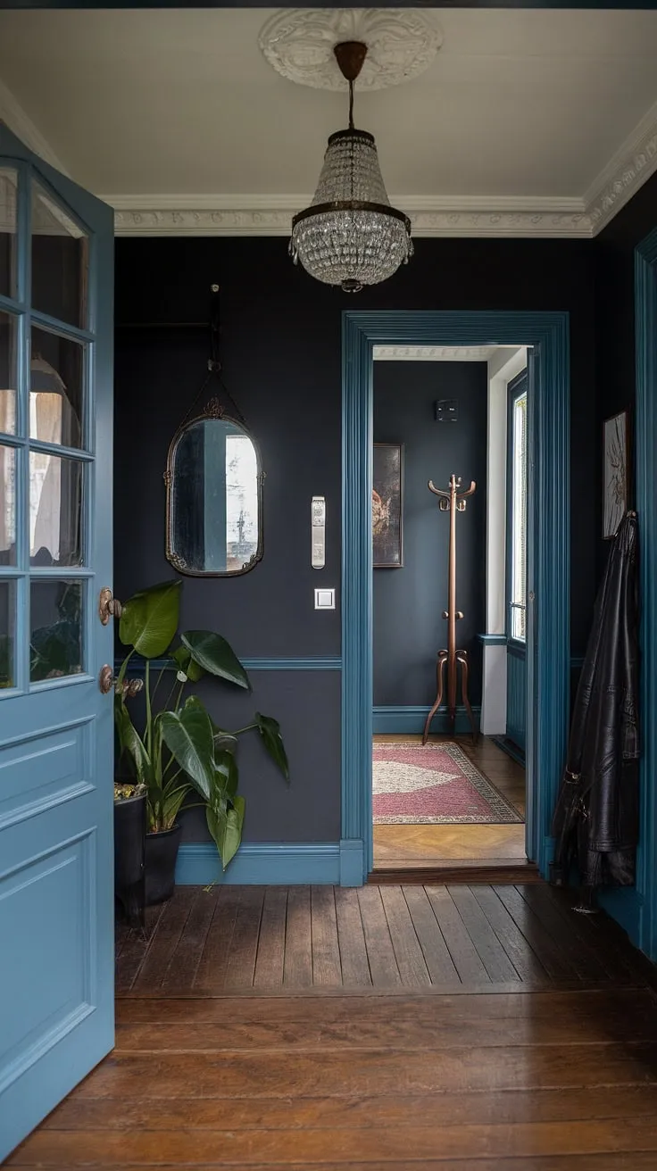A dramatic, dark blue entryway whispers tales of Victorian elegance. The ornate chandelier casts a warm glow on the polished wood floors, while a glimpse through the open door reveals a hallway steeped in history, hinting at the mysteries held within. A touch of nature softens the rich, dark tones.